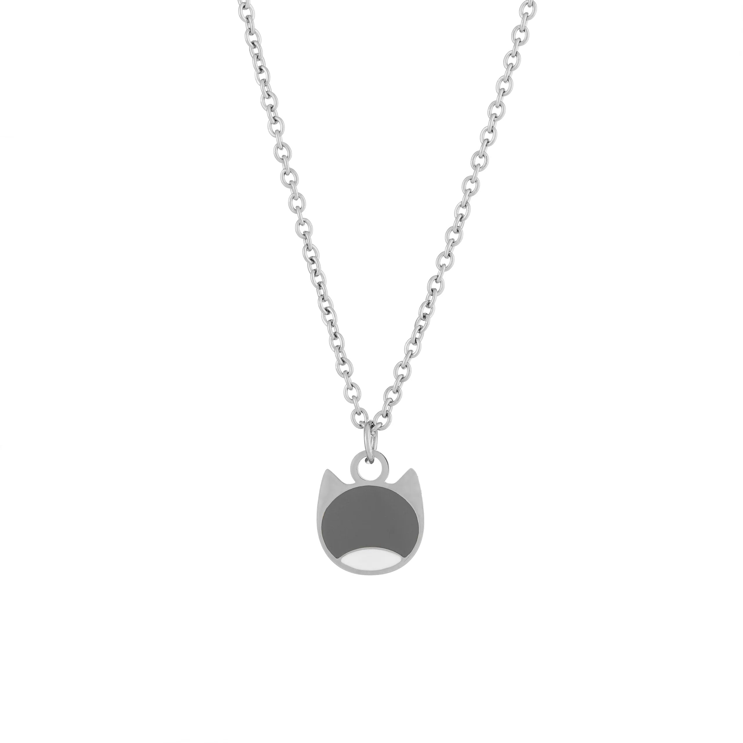 A silver chain necklace featuring a minimalist pendant shaped like a cat's face, with a dark gray top half and a white bottom half, shown against a plain white background.