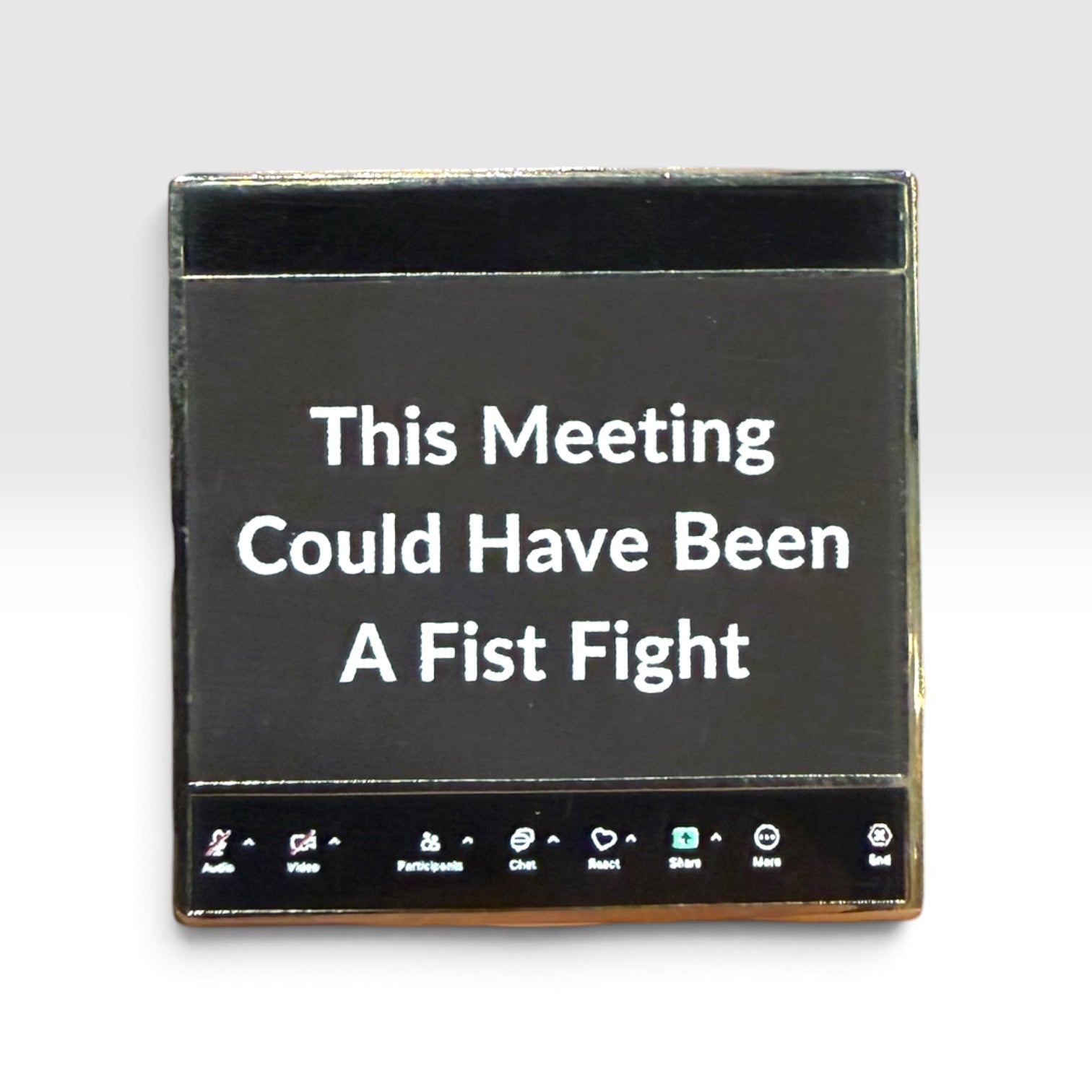 A square black enamel pin with a gold-toned metal border and a black magnetic backing. The front features white text that reads 'This Meeting Could Have Been A Fist Fight' with various meeting app icons along the bottom edge, set against a plain light gray background.