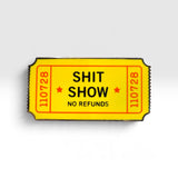 A novelty enamel pin shaped like a yellow movie ticket with the text 'SHIT SHOW NO REFUNDS' and red serial numbers, shown on a light gray background.
