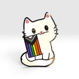A cute enamel pin shaped like a white cat holding a rainbow-striped flag, shown on a clean white background.