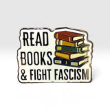 An enamel pin with a white background and a wavy black border, featuring the text 'READ BOOKS & FIGHT FASCISM' in black alongside an illustration of a stack of colorful books.