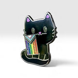 A black cat enamel pin holding a colorful pride flag, set against a clean light gray background.