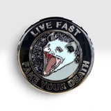 A circular enamel pin featuring a stylized possum face with its mouth wide open, surrounded by a black outer ring with the text 'LIVE FAST' and 'FAKE YOUR DEATH' in silver lettering.