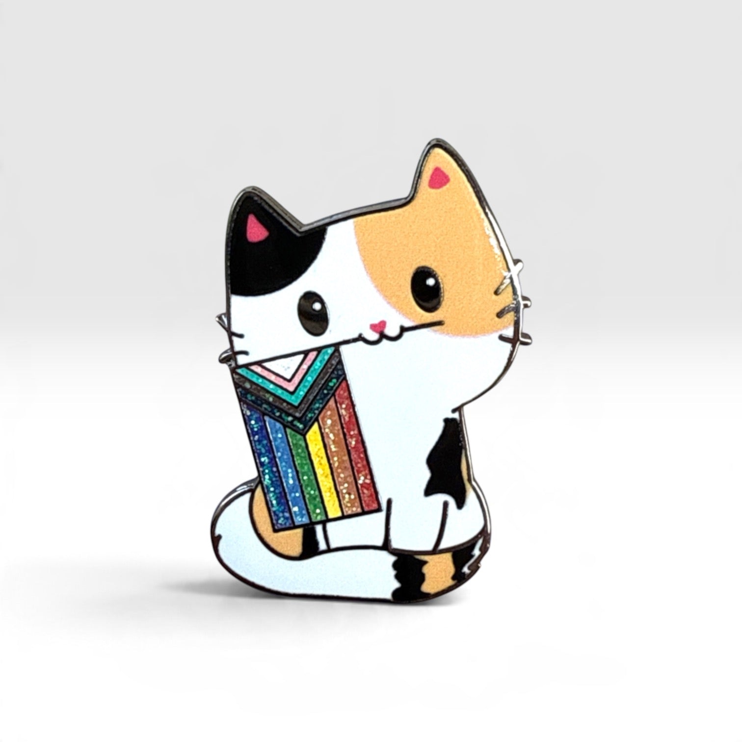 A cute cartoon cat enamel pin holding a colorful striped sweater, shown on a clean light gray background.