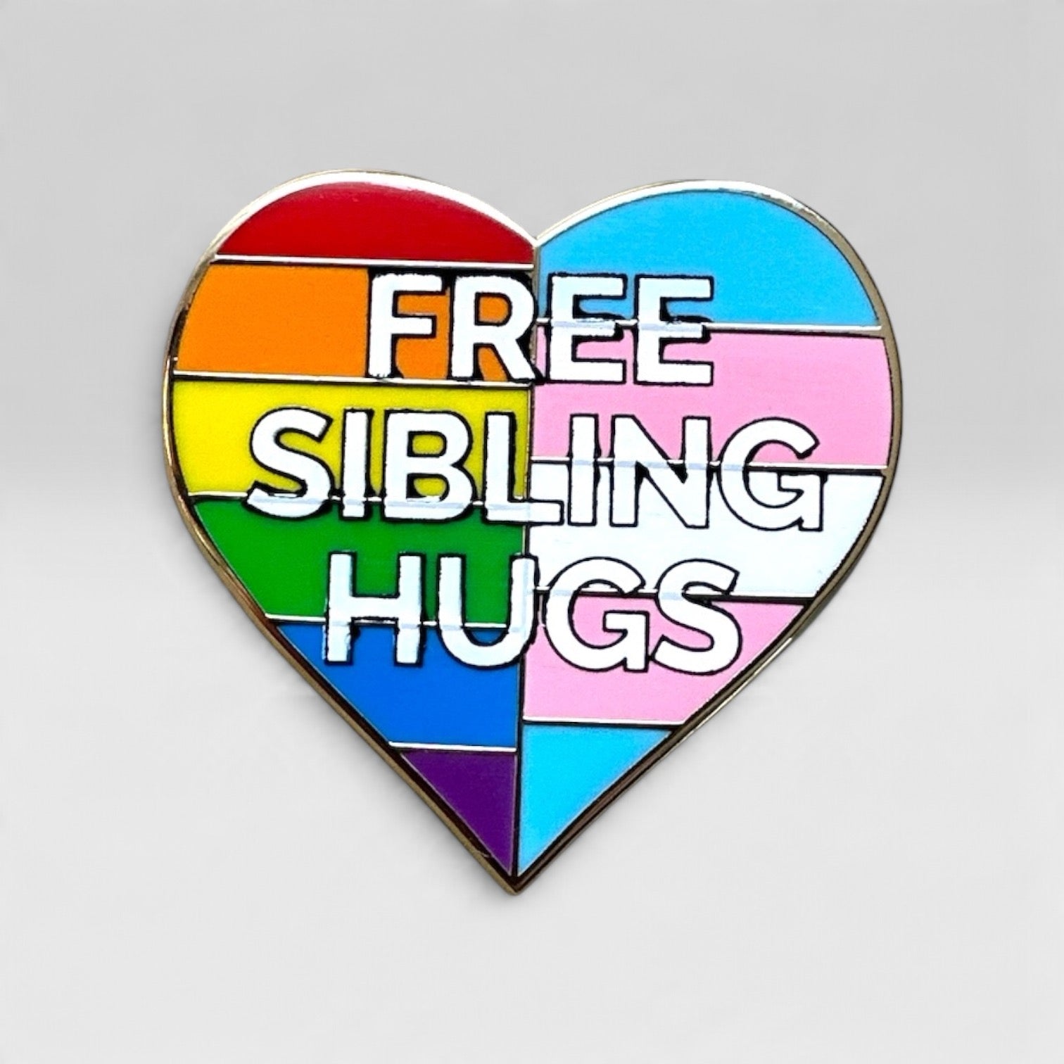 A heart-shaped enamel pin with a rainbow-striped design and the words 'FREE SIBLING HUGS' in bold white letters, shown on a light gray background.