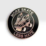 A circular enamel pin with roller skate graphics and the text 'MORE SKATE LESS HATE' on a light gray gradient background.