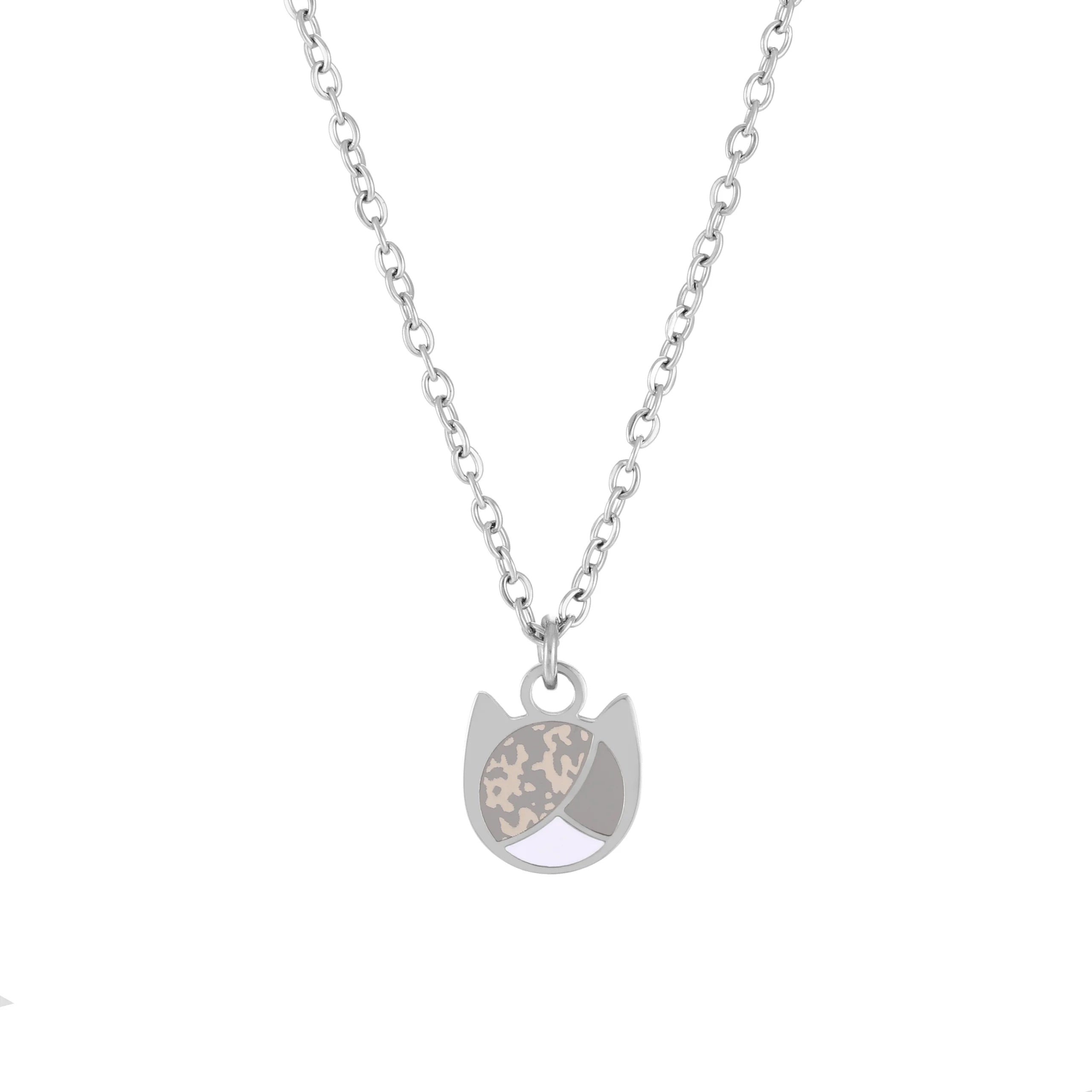 A silver-toned chain necklace with a cat-shaped pendant featuring a split design of textured beige and light gray enamel on a white background.