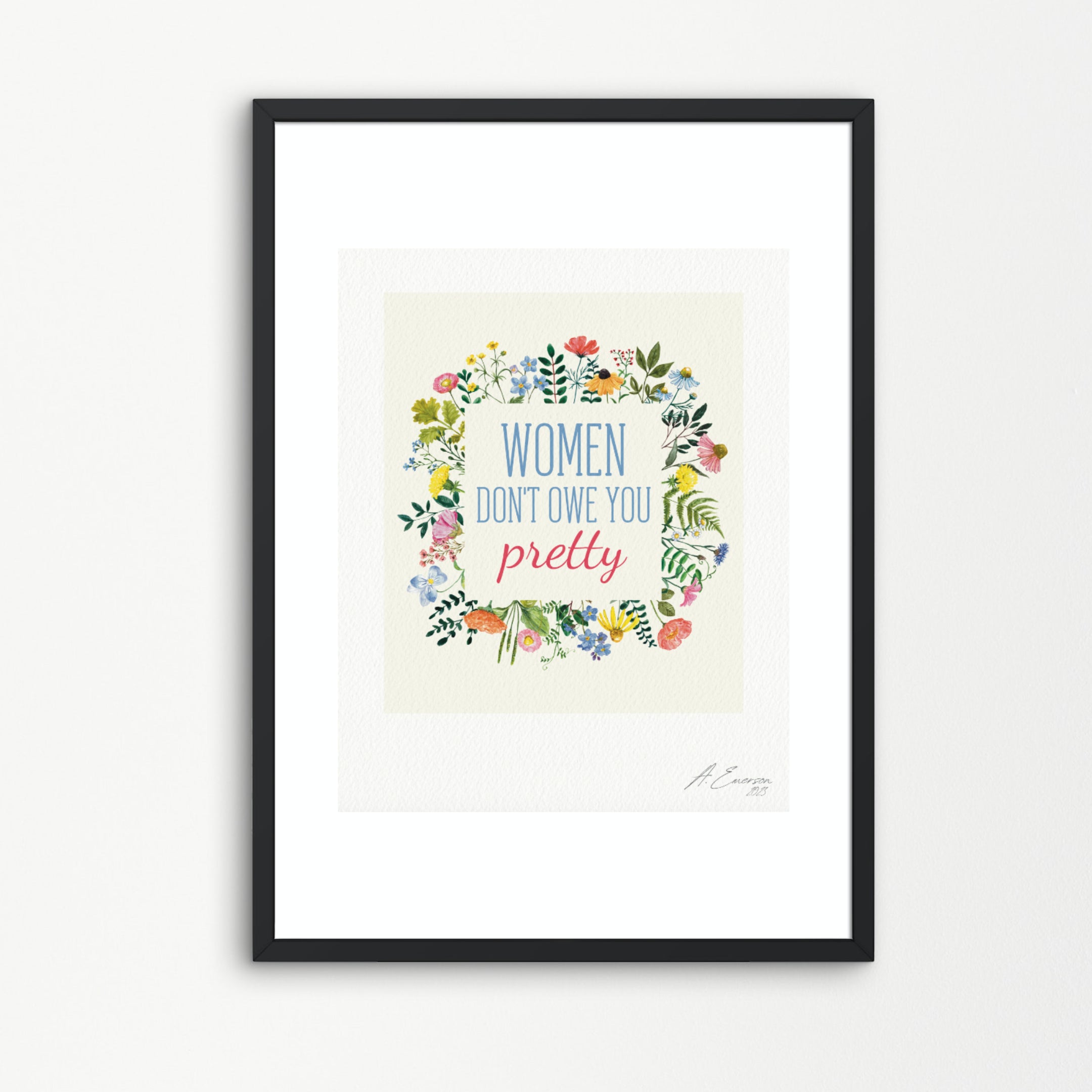 A framed art print featuring the quote 'WOMEN DON'T OWE YOU pretty' surrounded by a colorful floral wreath, displayed on a clean white background.