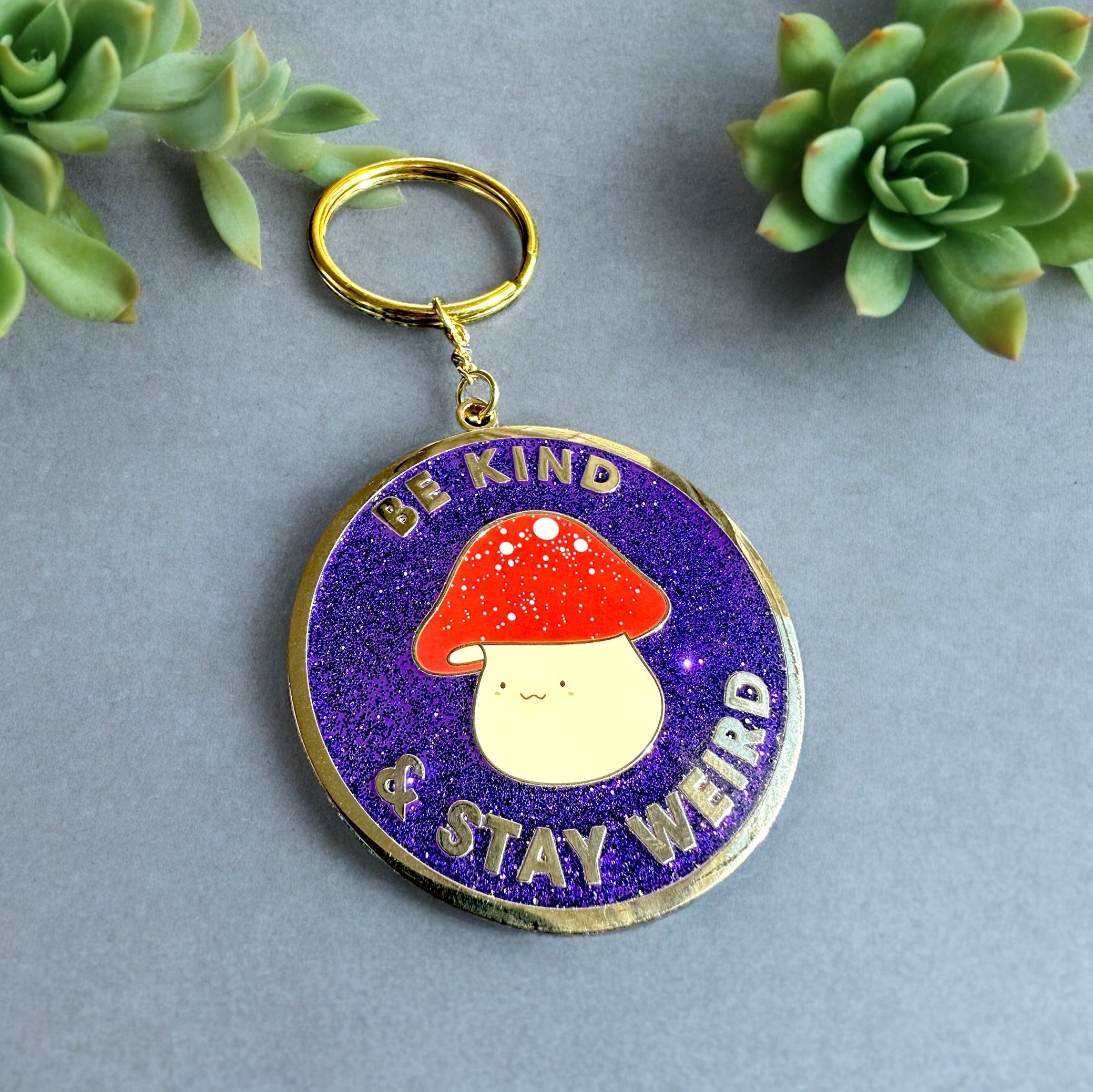 Be Kind & Stay Weird enamel keychain with hand-lettered text in gold plating
