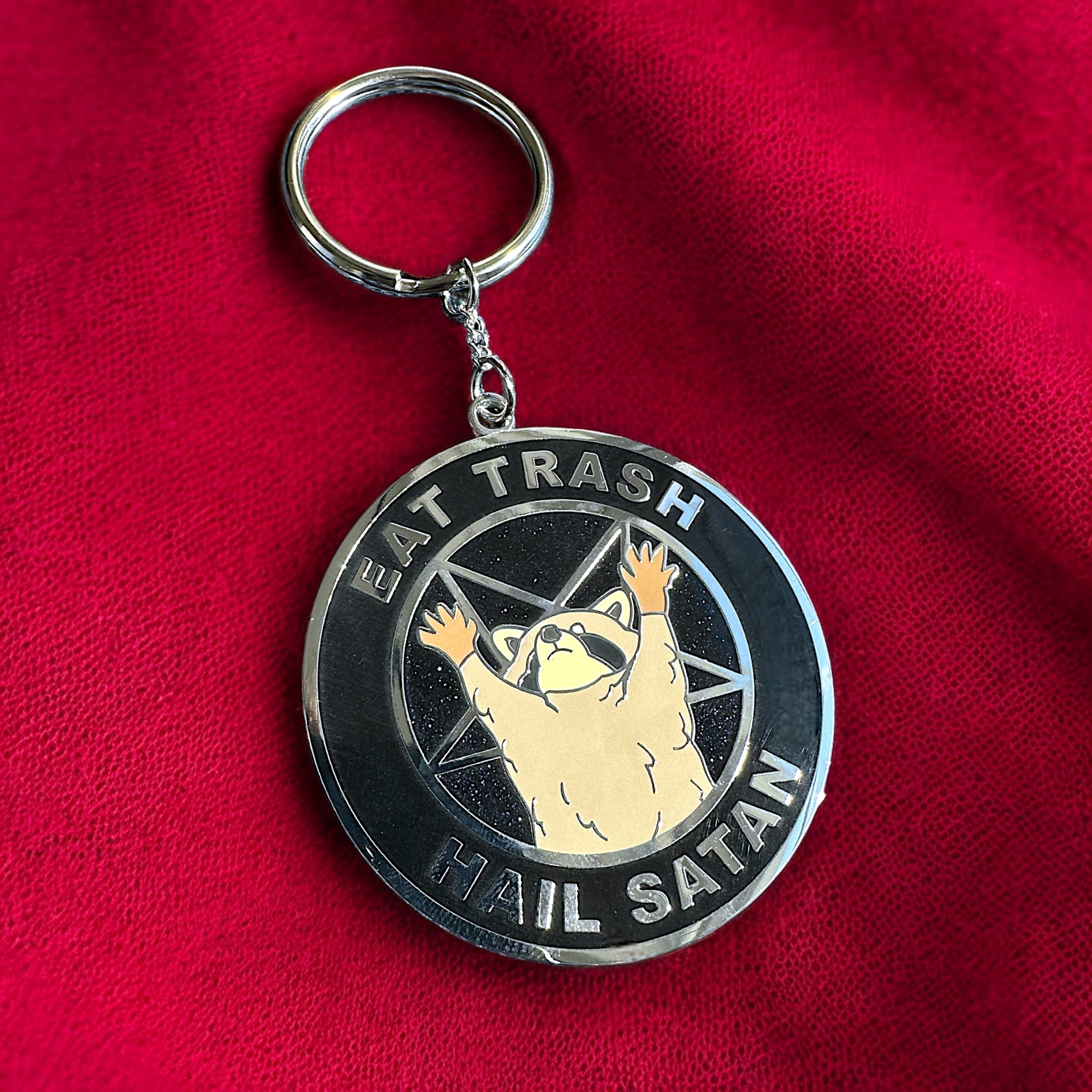 Eat Trash Hail Satan enamel keychain featuring a raccoon in black chrome plating