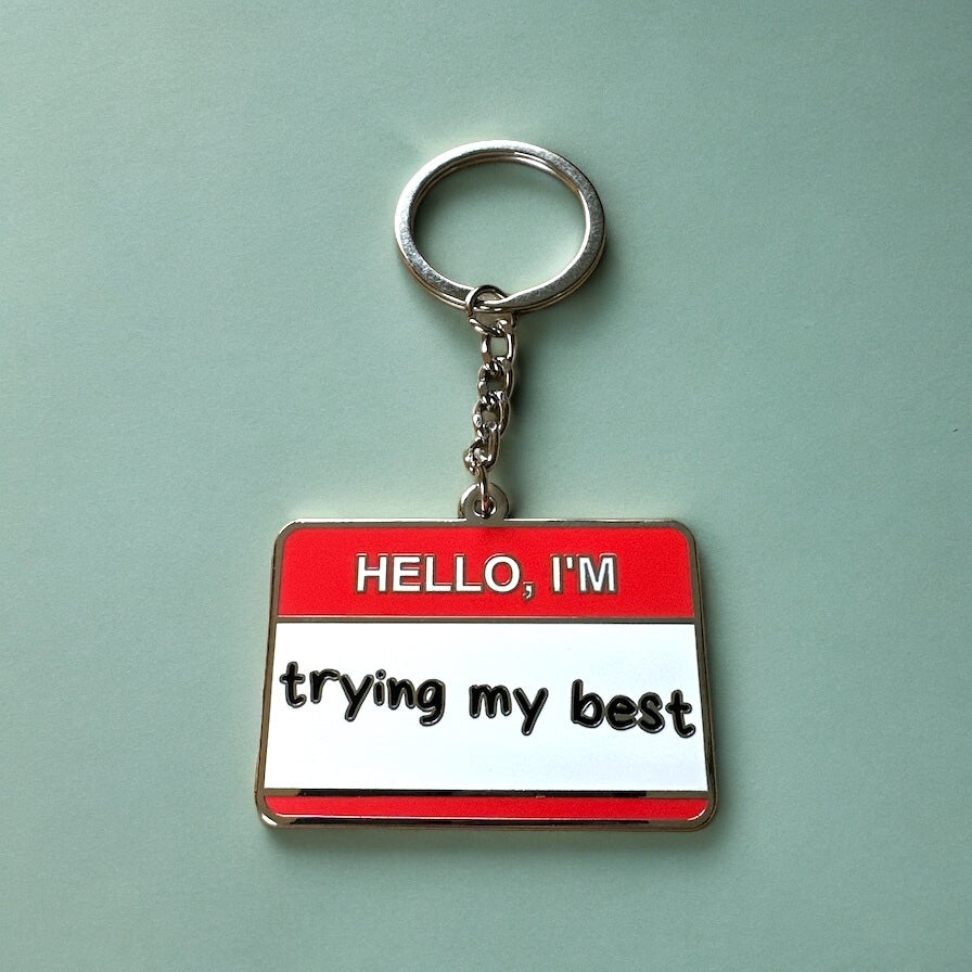 Hello I'm Trying My Best enamel keychain designed as a name tag in red and white