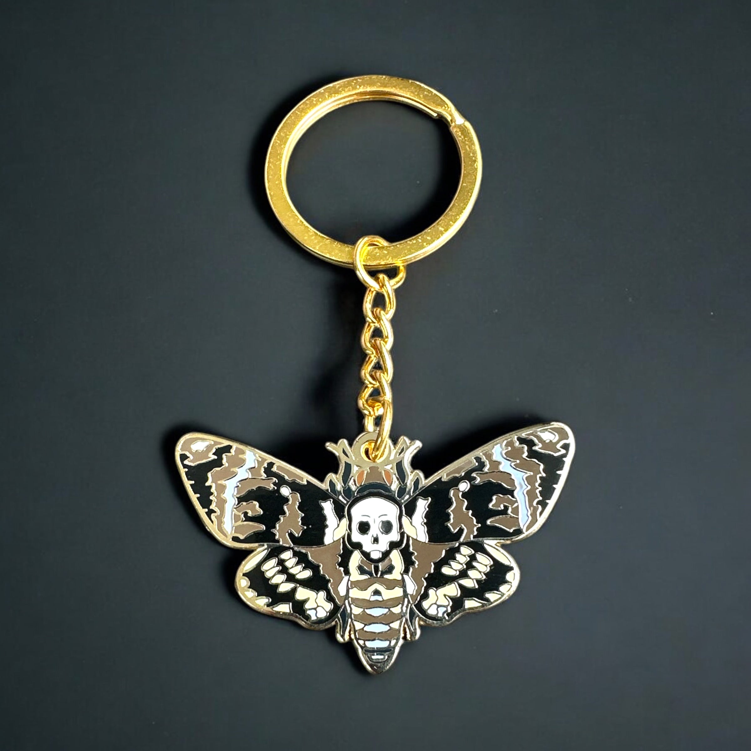 Death's-head hawkmoth enamel keychain showing the signature skull marking in brown and gold