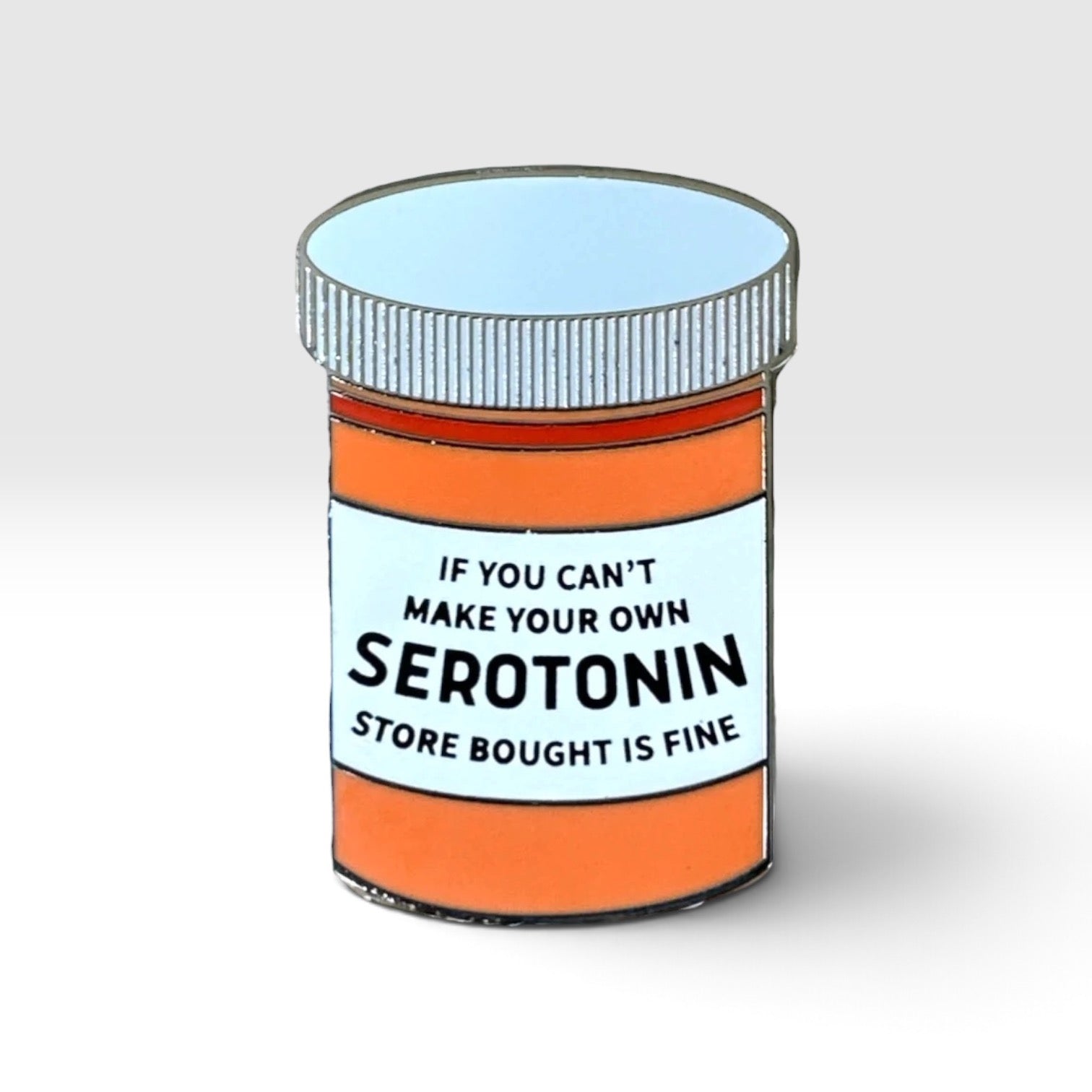 Enamel pin shaped like an rx pill bottle with the words "If you can't make your own serotonin store bought is fine" on it.