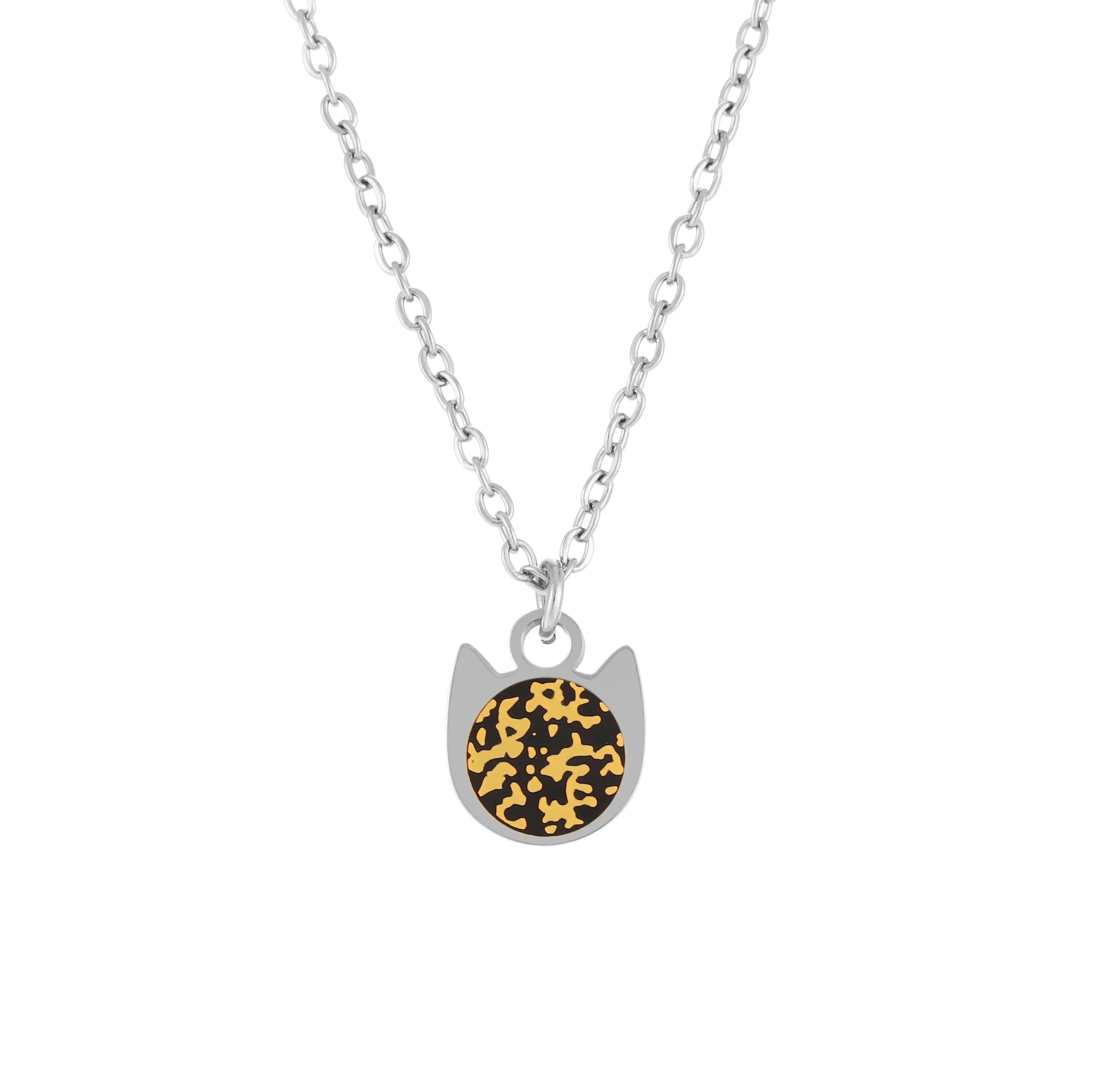 A silver cat-shaped pendant necklace featuring a circular black and gold patterned center, suspended from a delicate silver chain against a plain white background.
